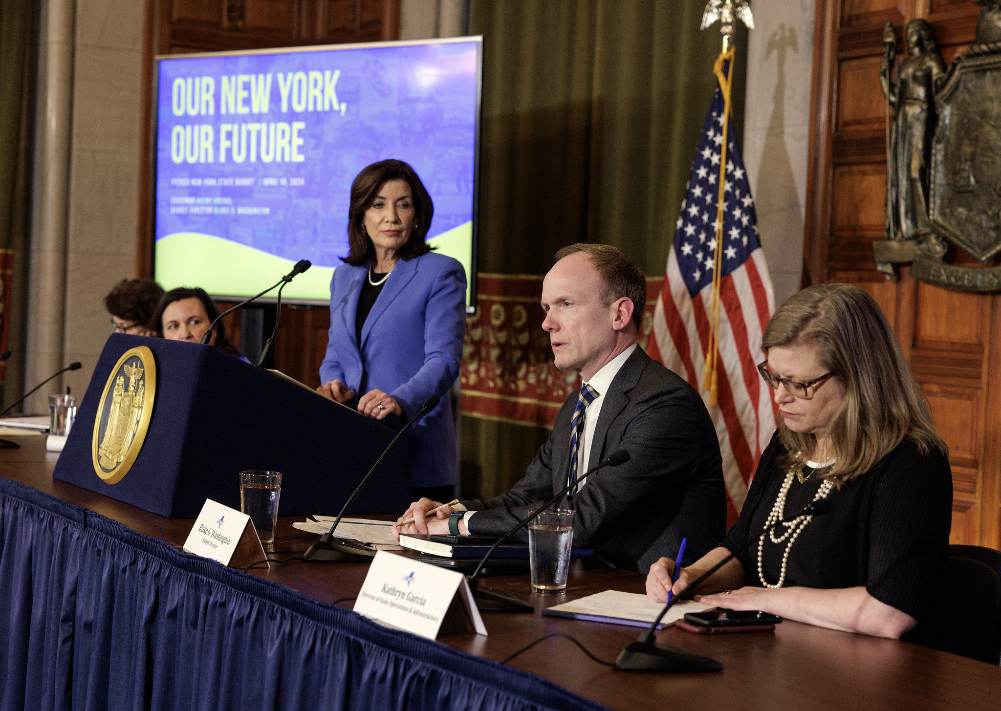 Gov. Kathy Hochul, standing alongside members of her cabinet, speaks at a press conference announcing a handshake deal on the state budget.