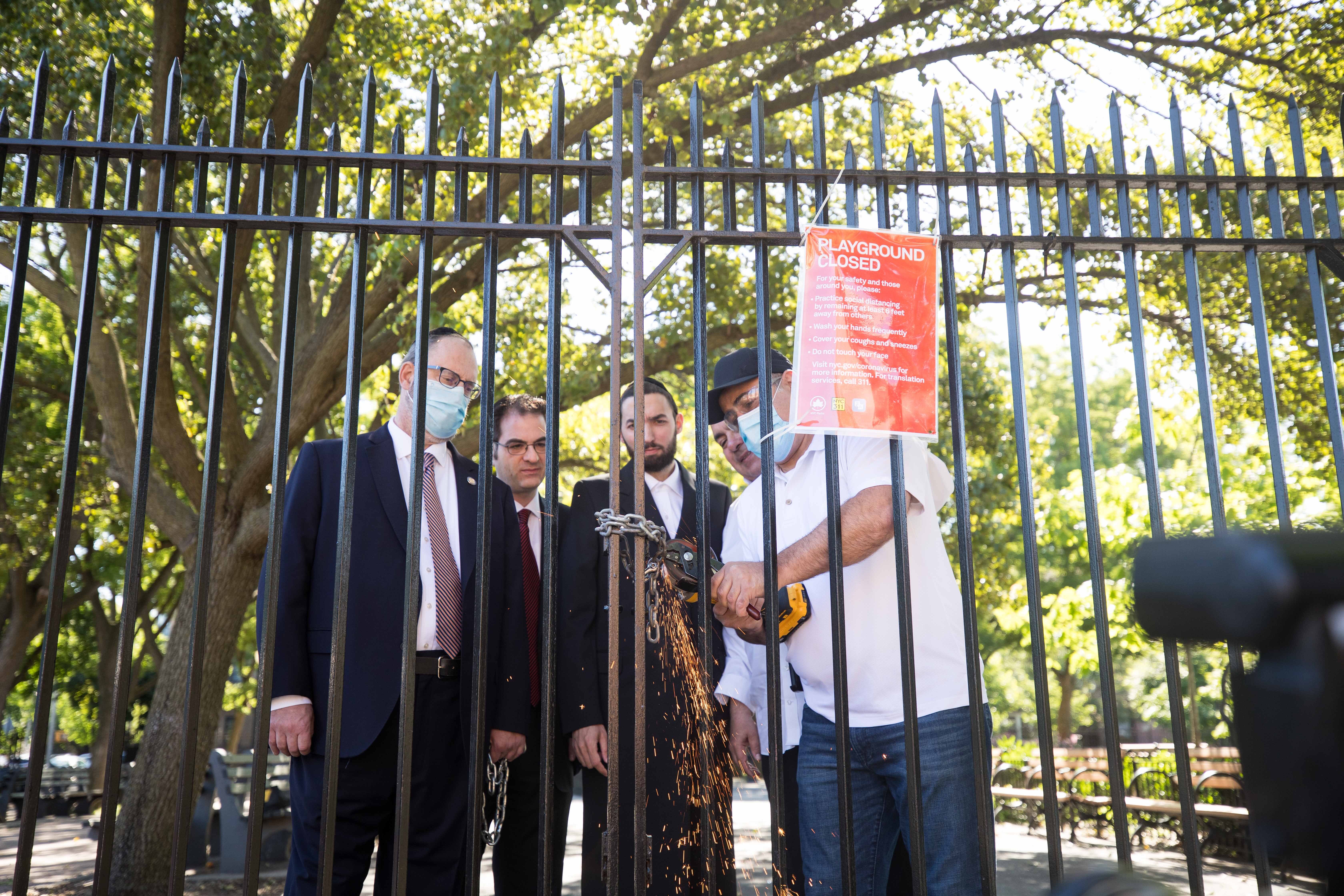 Councilman Kalman Yeger, Assemblyman Simcha Eichenstein, Senator Simcha Felder and an unidentified worker cut the lock at a Brooklyn playground.