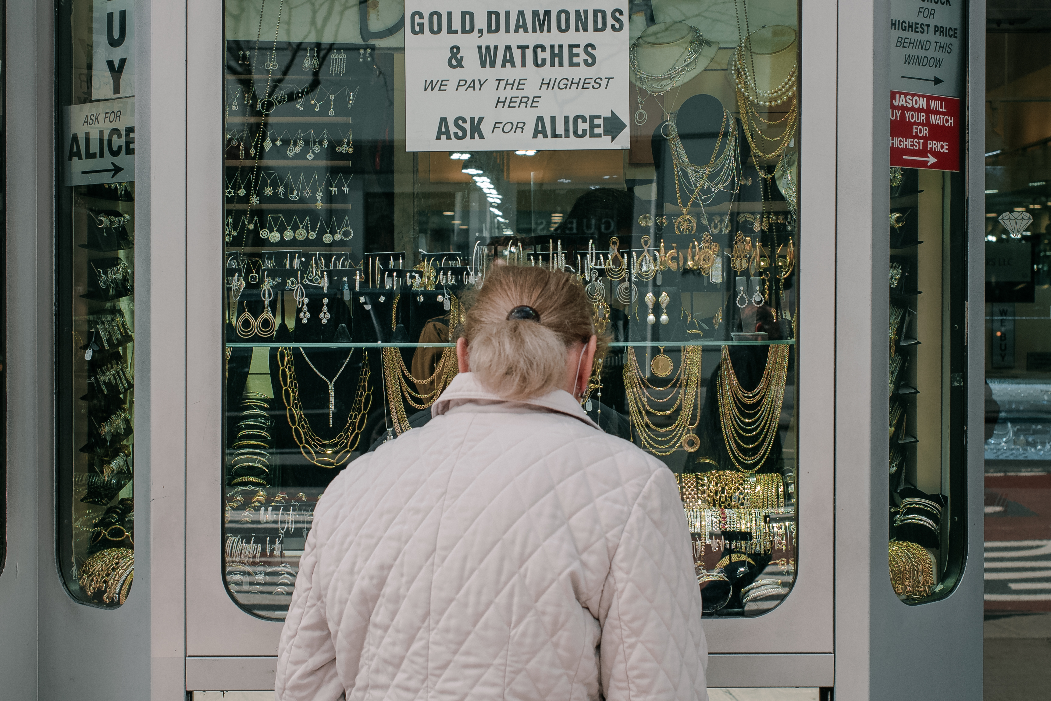 A photo of a woman looking at jewelry in a store window