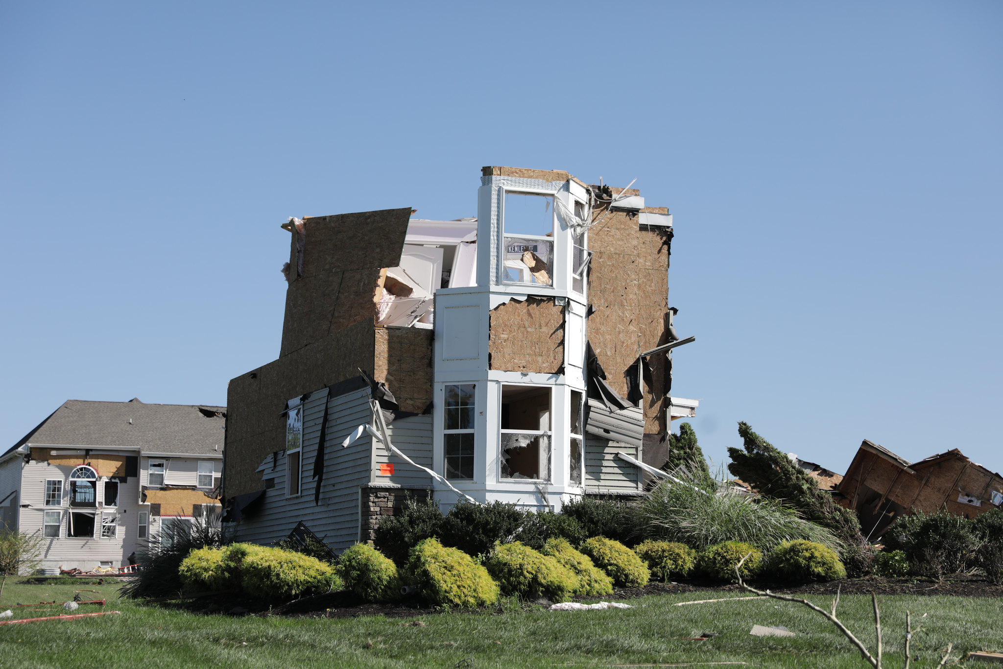 The top floor of a two story house is partly sheared off, with no roof