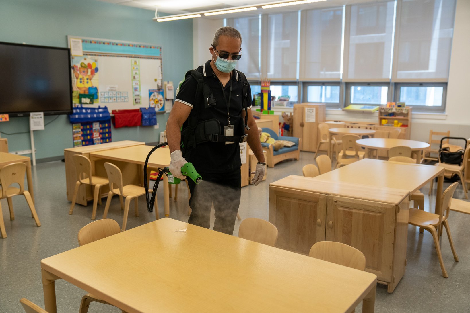 The city Department of Education released this photo of an employee spraying a school desk and cleaning.