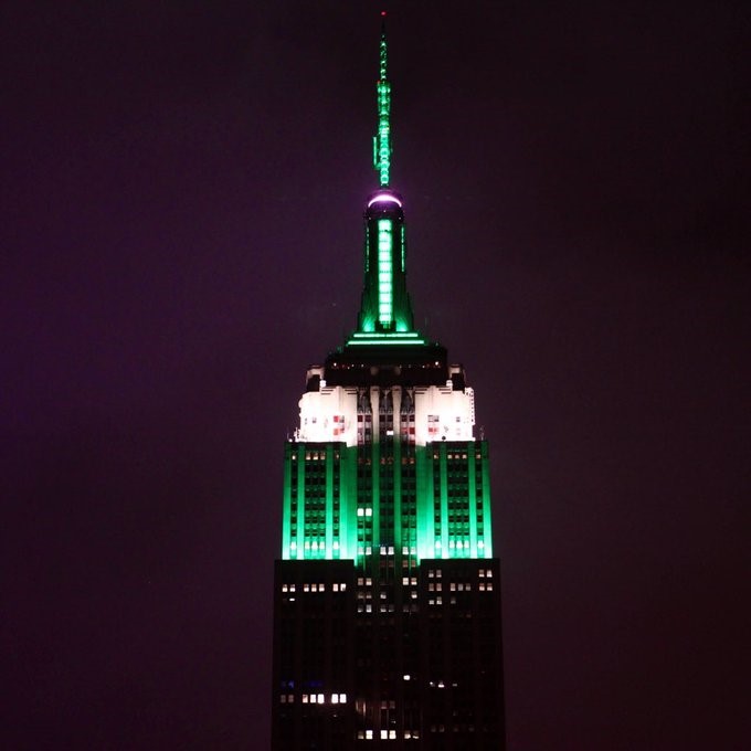 The Empire State building is illuminated in green and white.