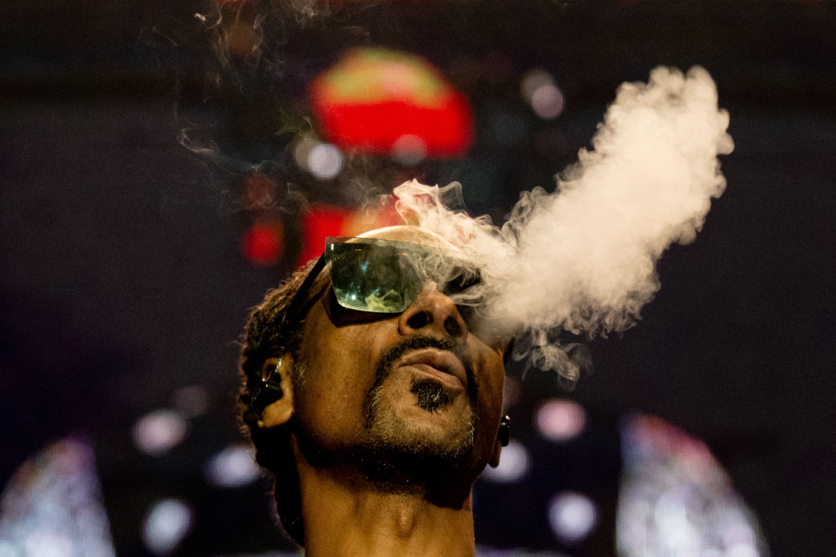 A close up of rapper Snoop Dogg blowing smoke.