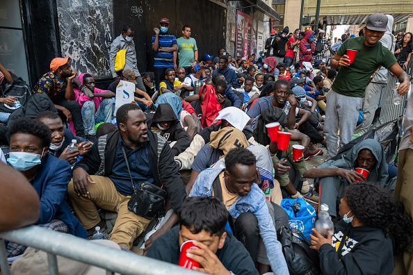 Photo of migrants on the sidewalk outside the Roosevelt Hotel.