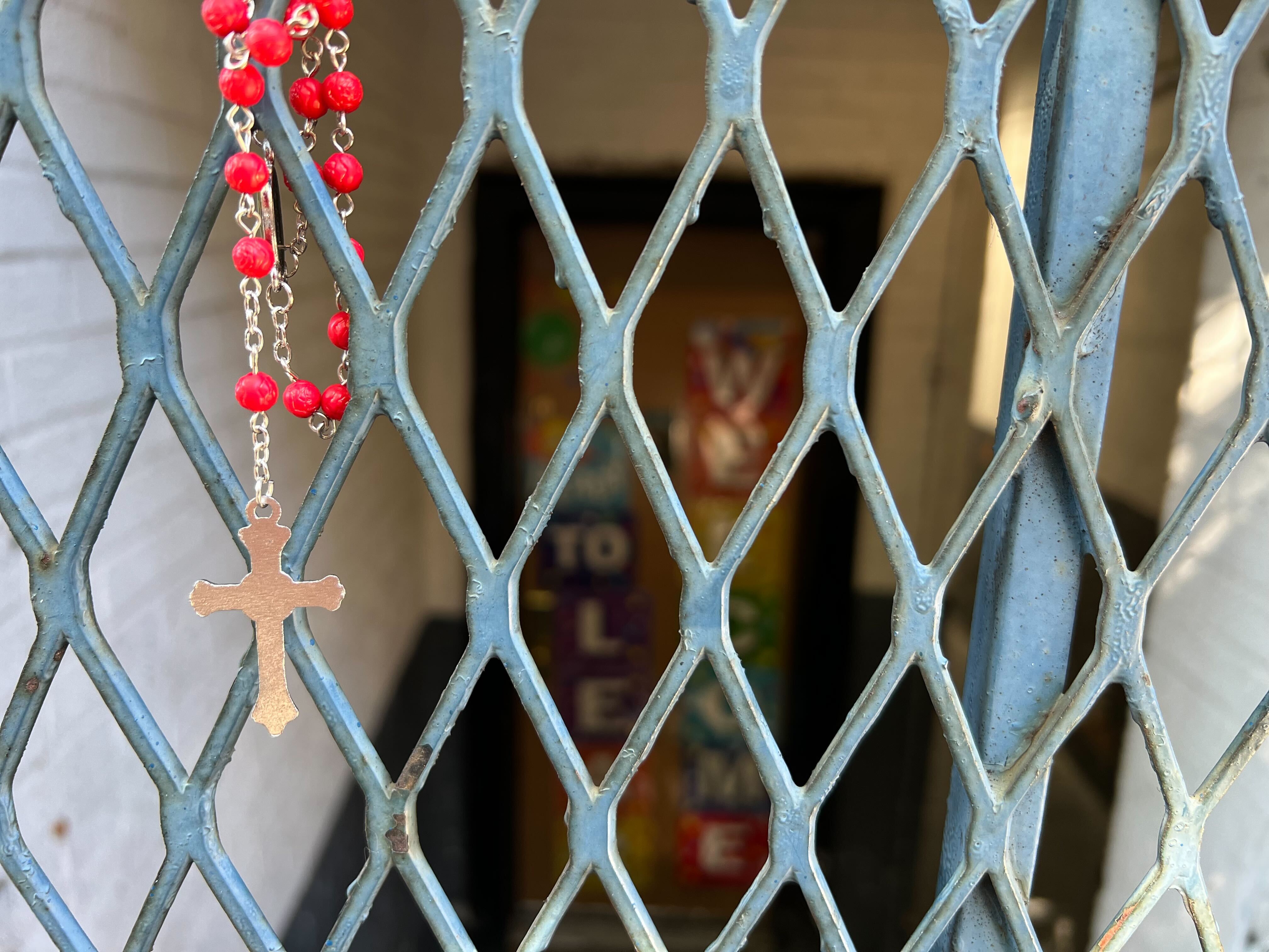 A rosary hangs on a metal gate outside of a Bronx daycare where a 1-year-old boy died after being exposed to opioids on Friday.