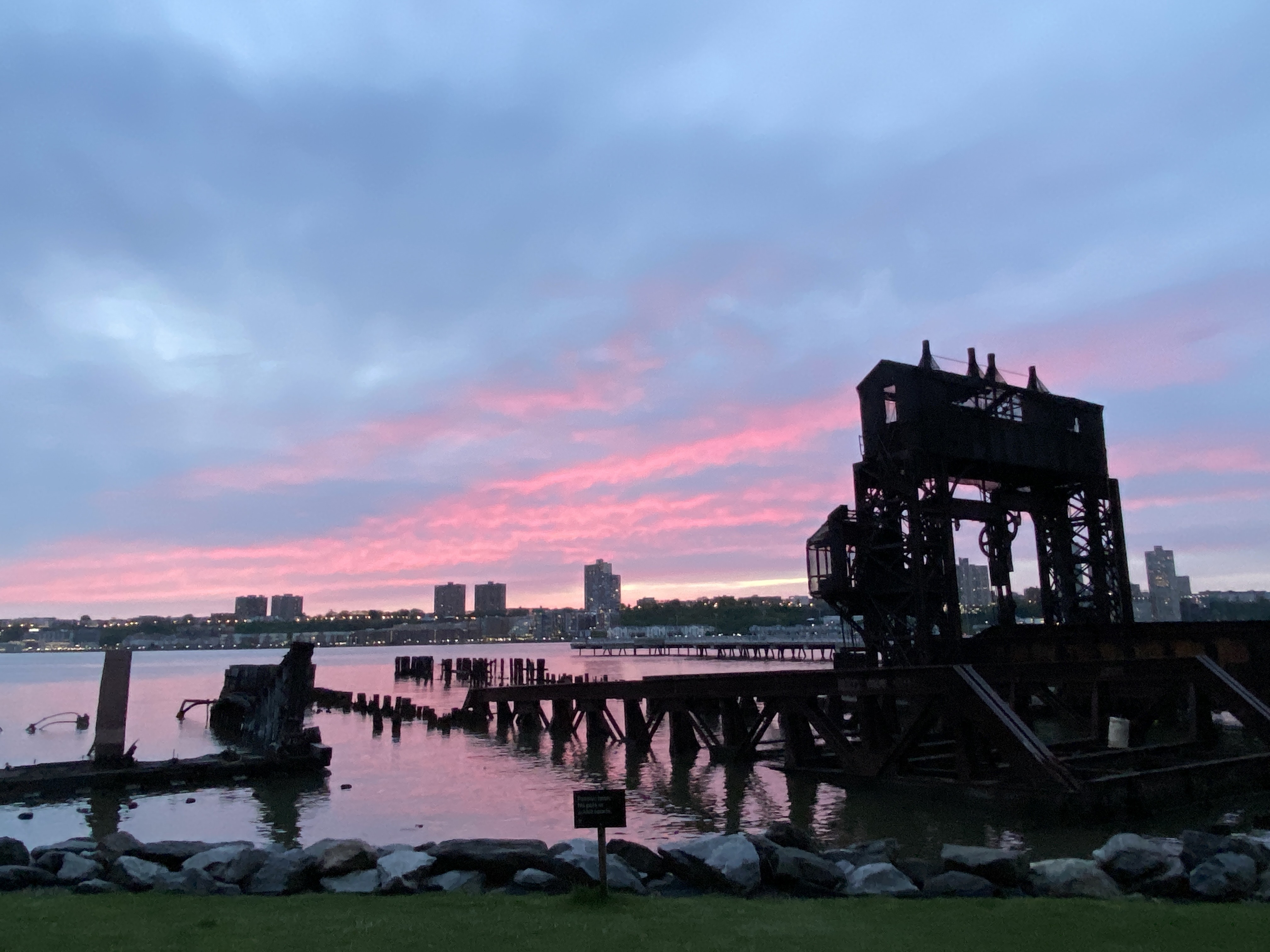 The old remains of a 19th century train transfer bridge in the Hudson River with a beautiful pink and blue sunset