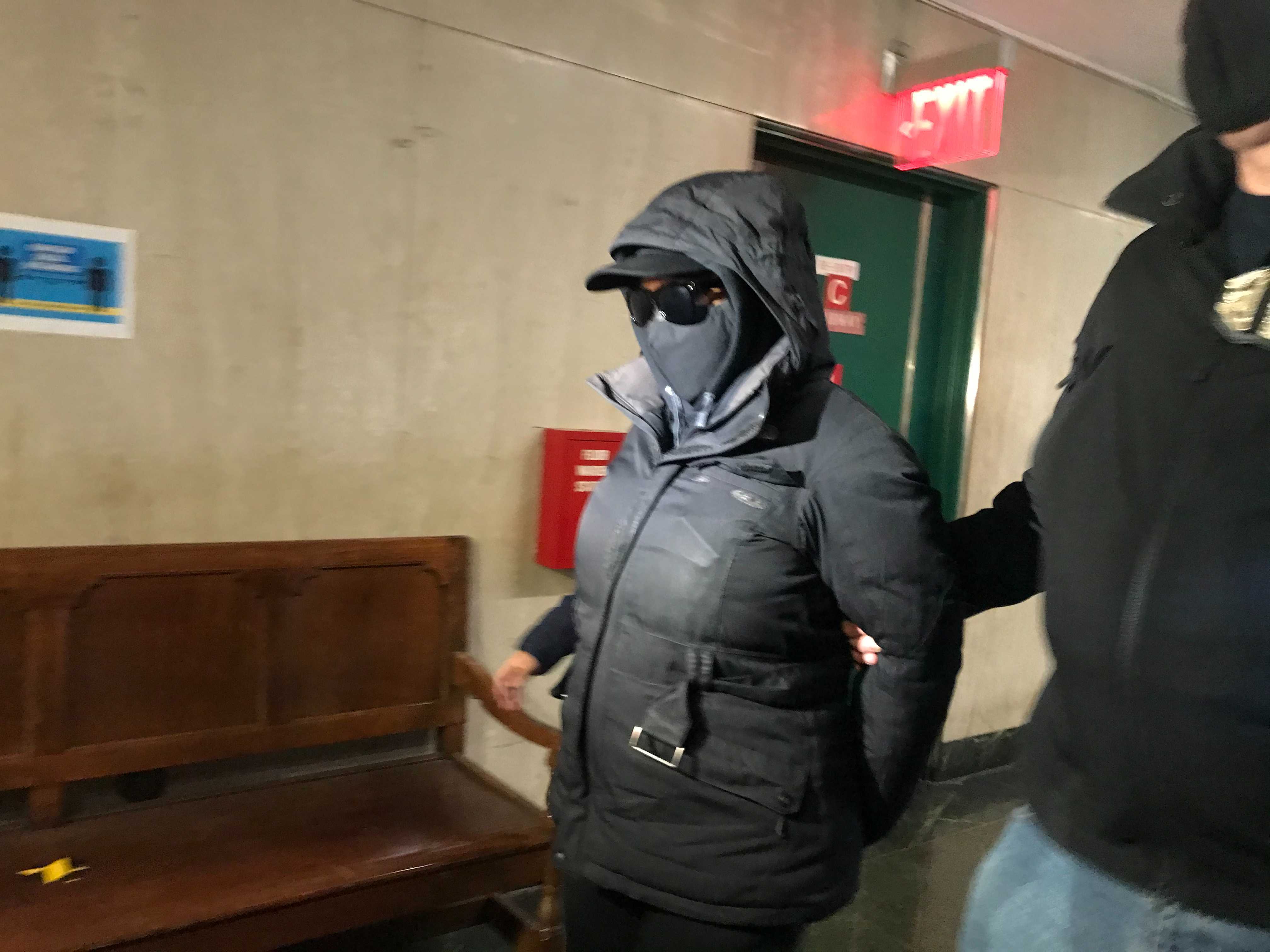 Captain Rebecca Hillman, her face obscured by a mask and sunglasses, appearing in court for her arraignment.
