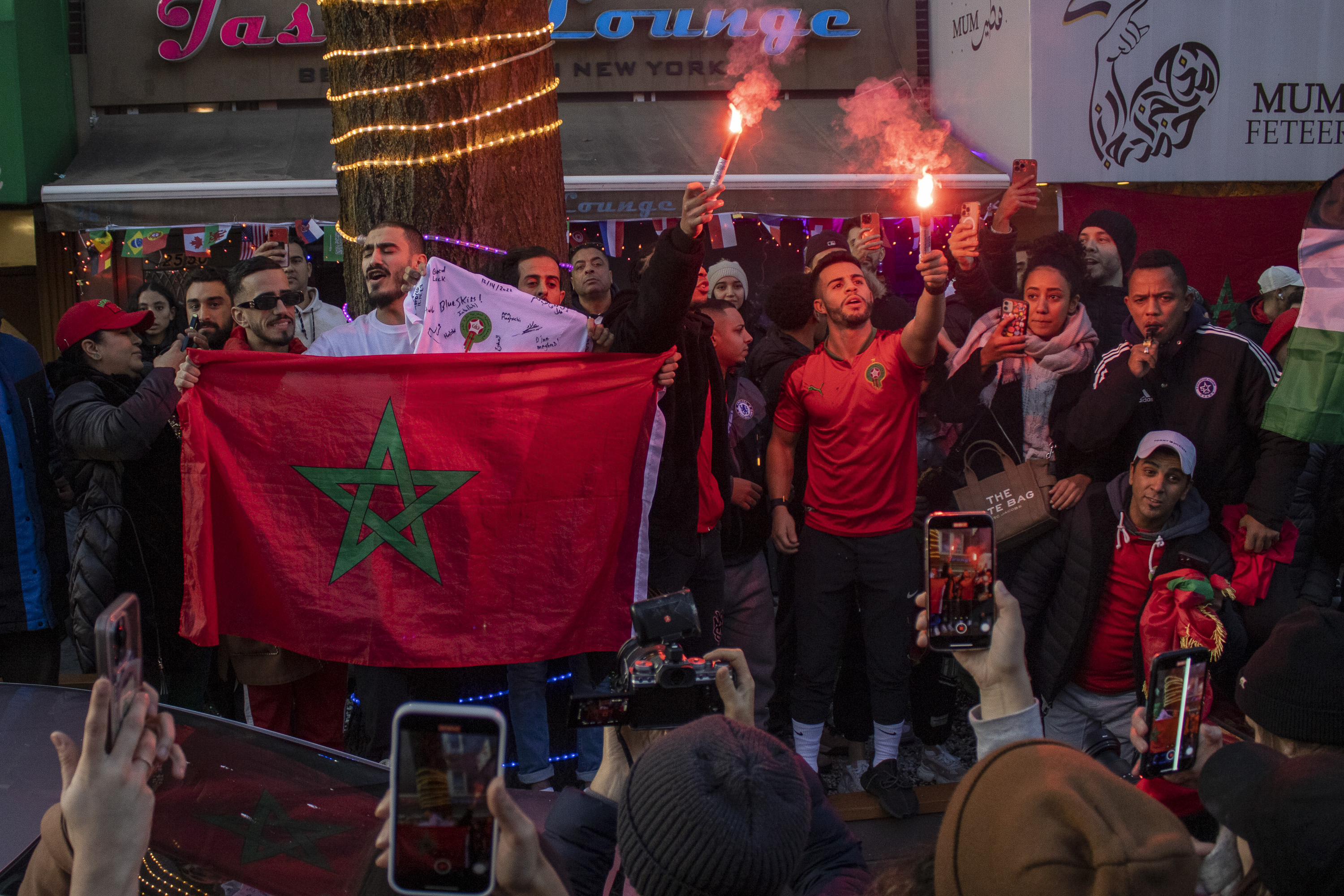 A group of fans of the Moroccan soccer team light streamers and hold the country's green and red flagathered outside of a bar in Queens.