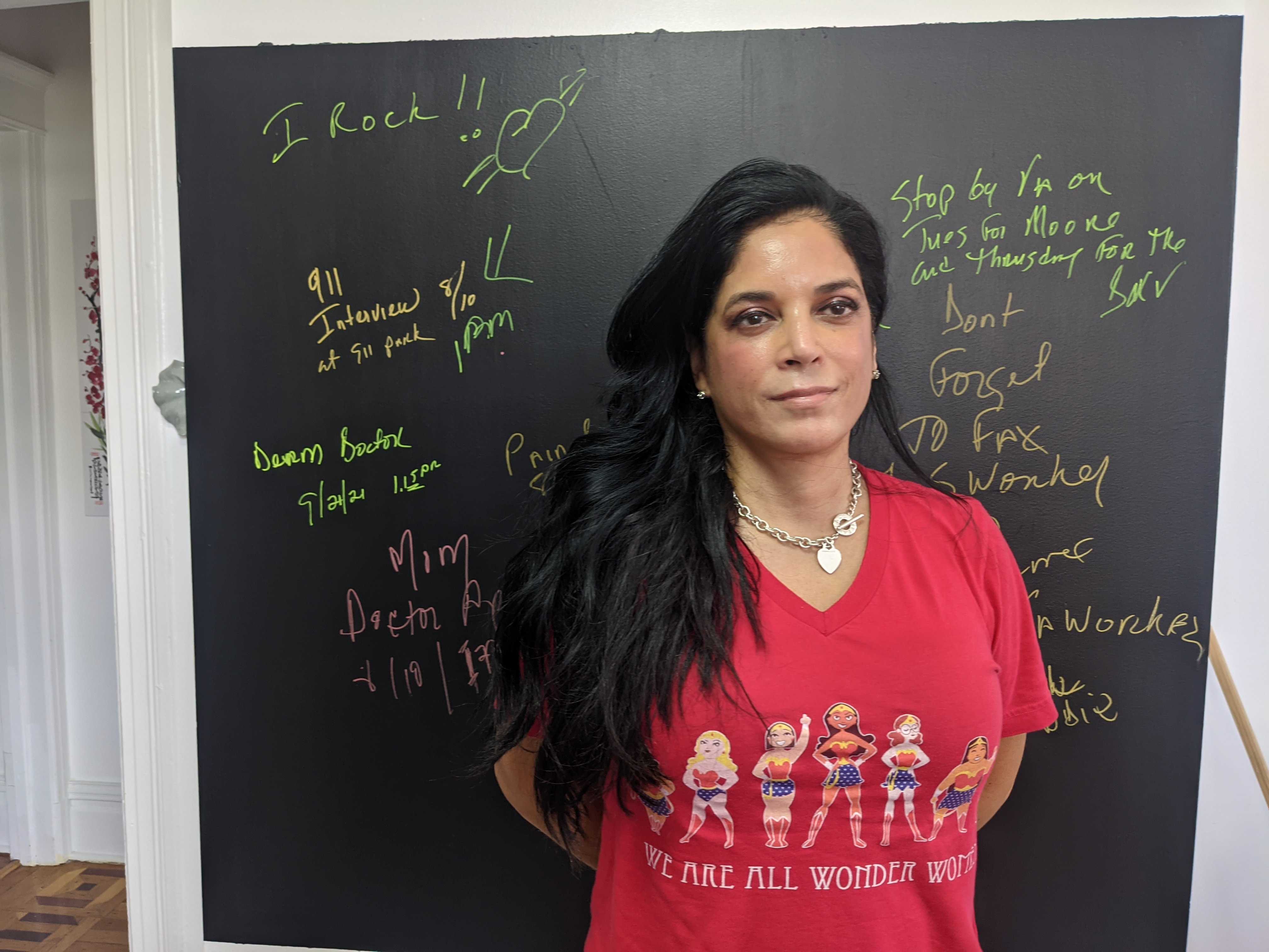 Ivonee Sanchez, in a red shirt, stands in front of a painting