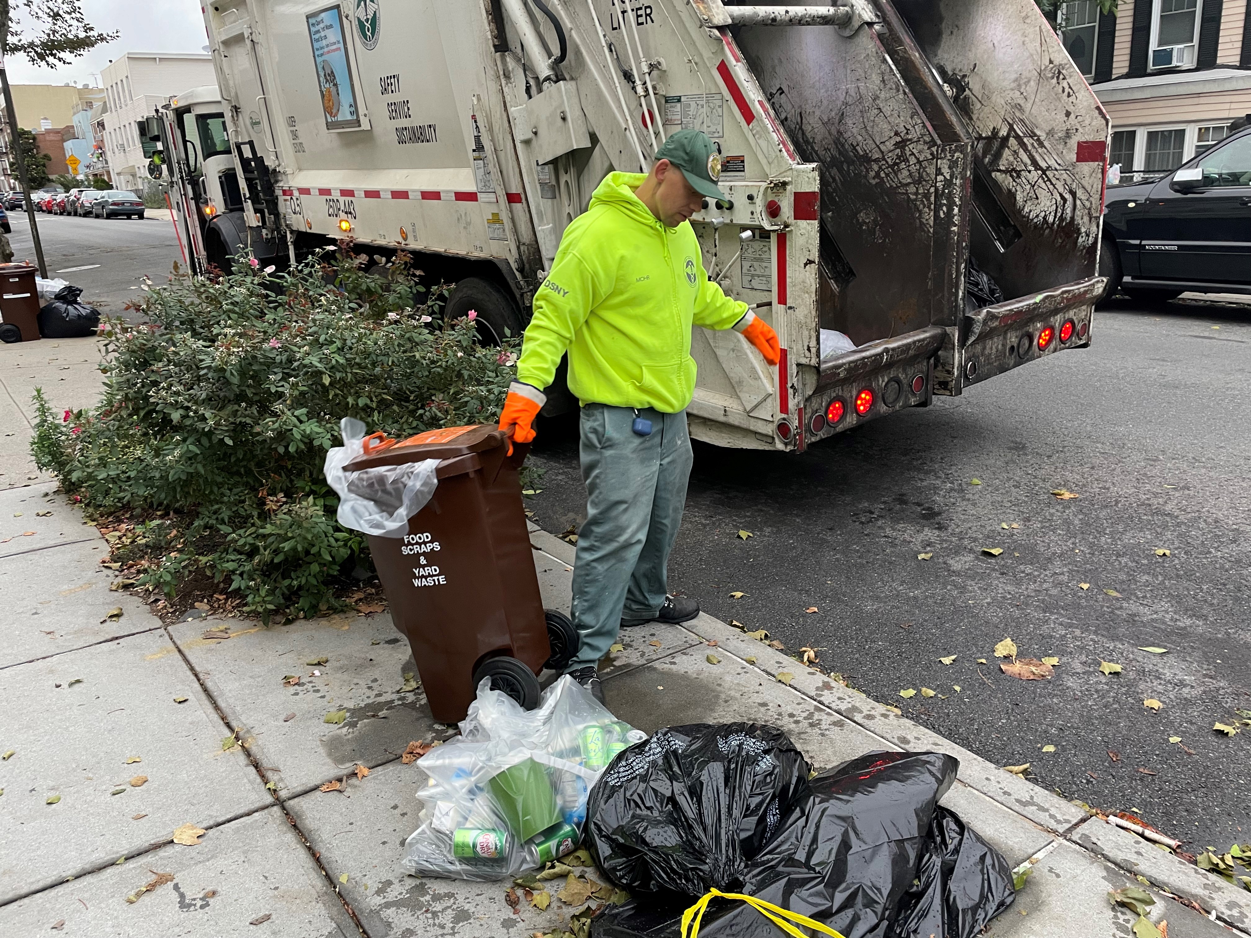 A sanitation worker dragging a bin for composting