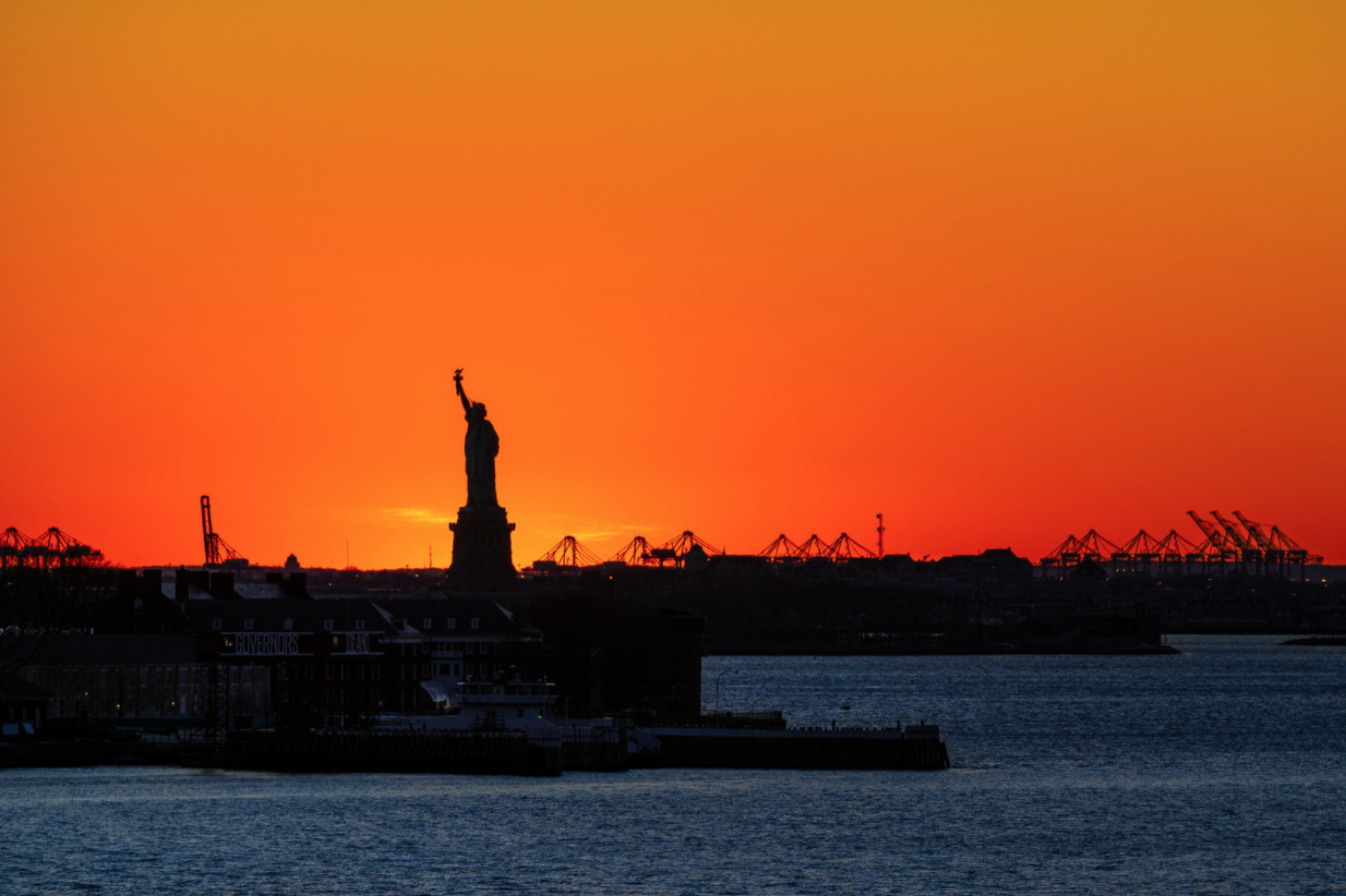A photo of the statue of liberty during an orange sunset