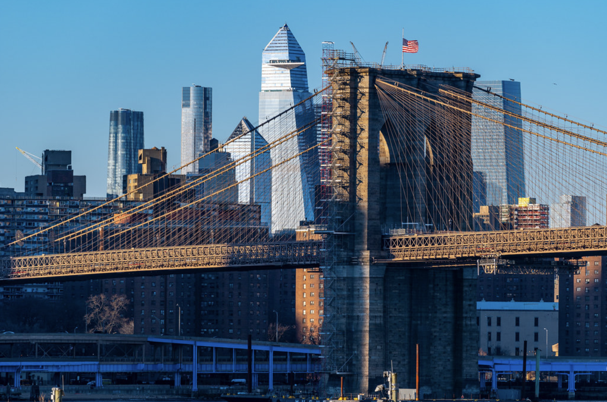 A view of the Brooklyn Bridge with the Manhattan skyline in the background.
