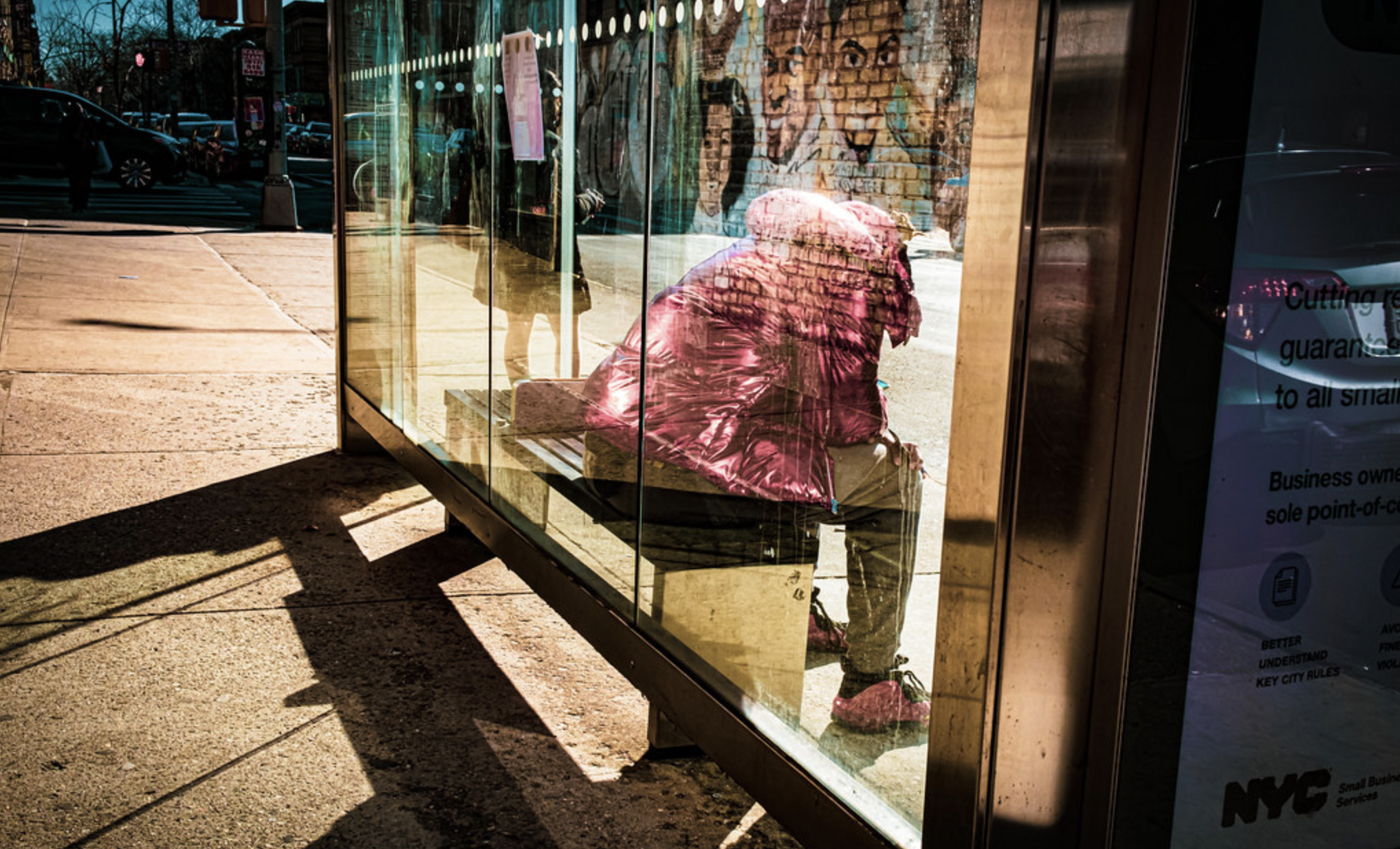 a guy in a pink jacket waits for the bus