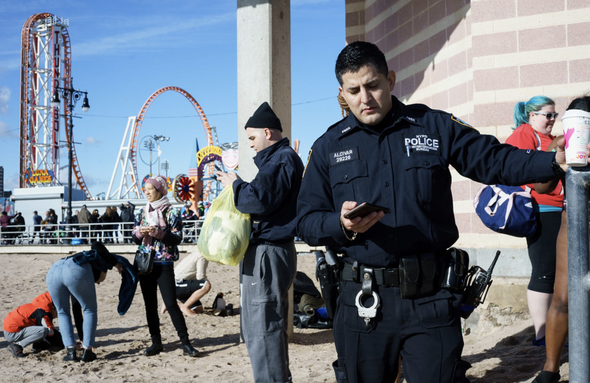 a cop staring at his phone in Coney Island