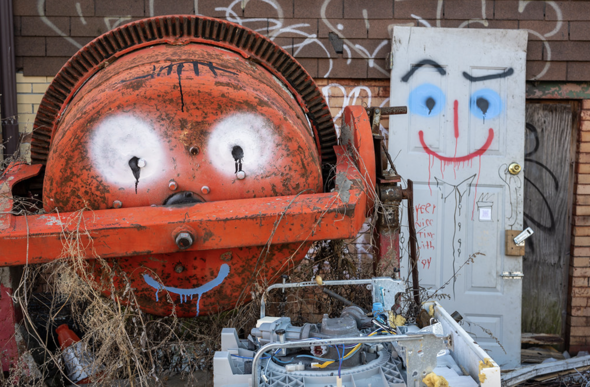 a trash can and a discarded door with faces painted on them