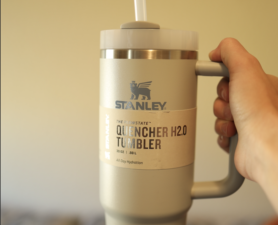 A person holds up a Stanley tumbler.