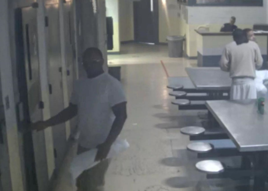 A surveillance image of James Albert walking into his cell with an unidentified package.
