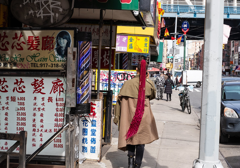 a woman with a long red braid walks through Chinatown