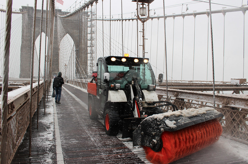 a snow plow clears the Brooklyn Bridge walkway
