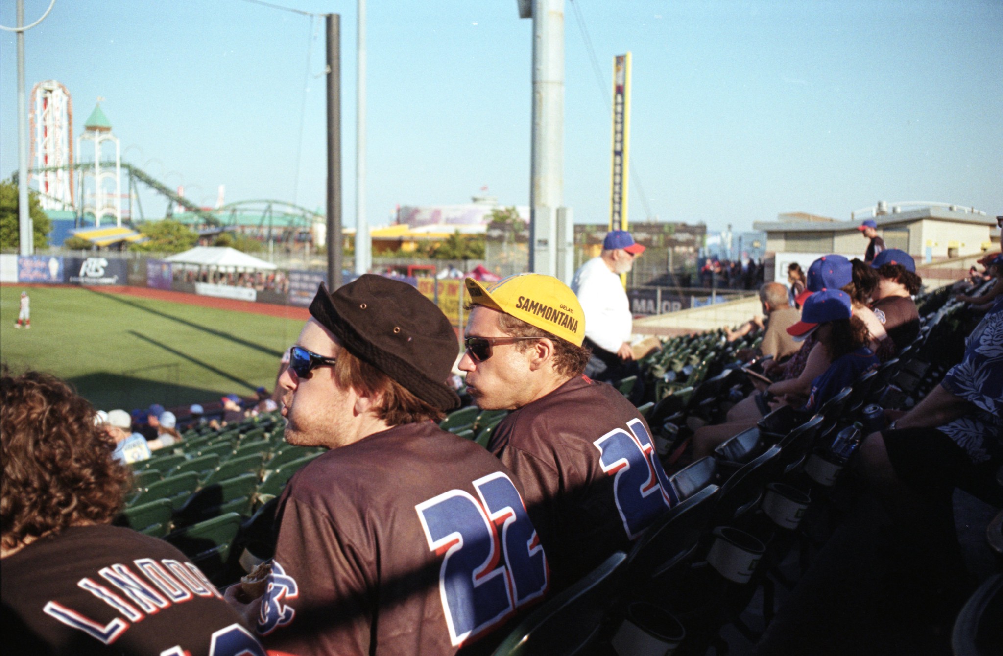 guys in funny hats sit in the bleachers at a Coney Island Cyclones baseball game