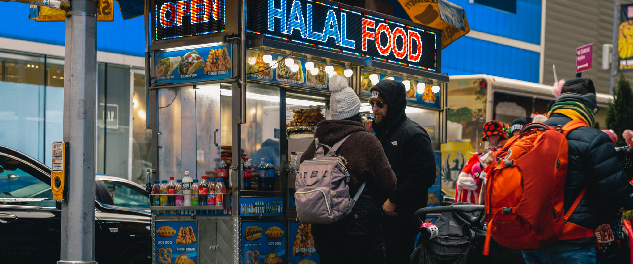 a bundled-up couple stand at a Halal cart