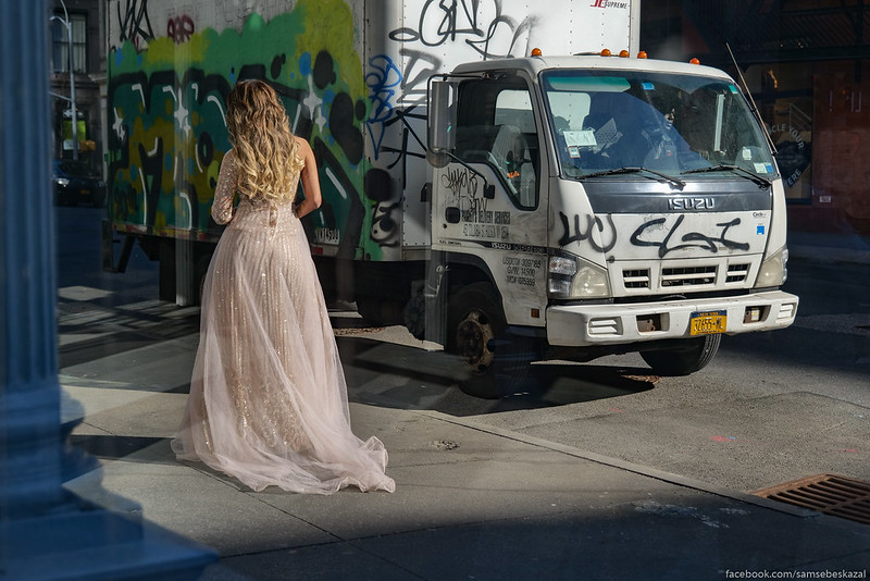 a woman in a gown stands outside a subway entrance