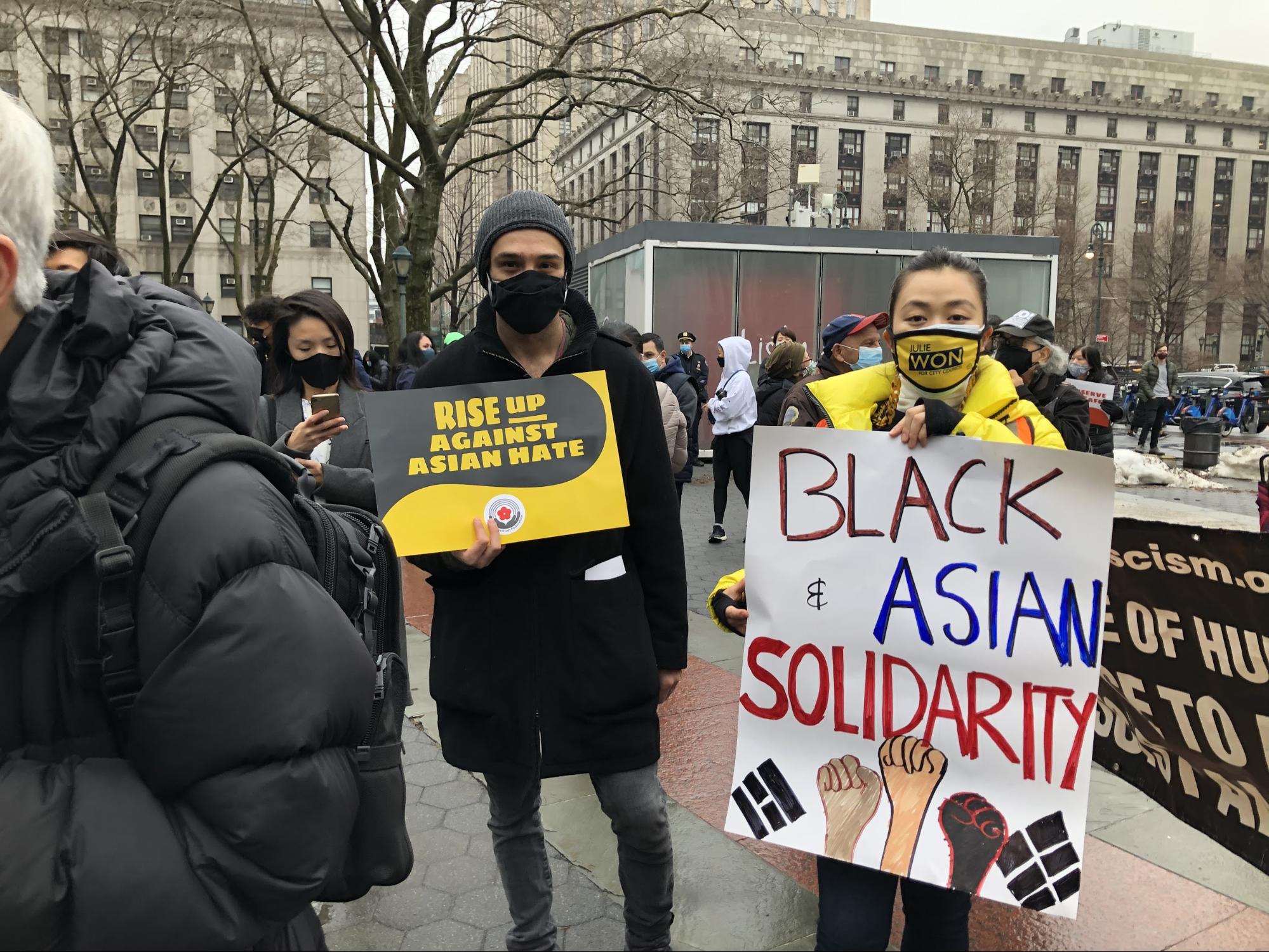 People hold signs at the rally, including a sign that says "Black and Asian Solidarity"