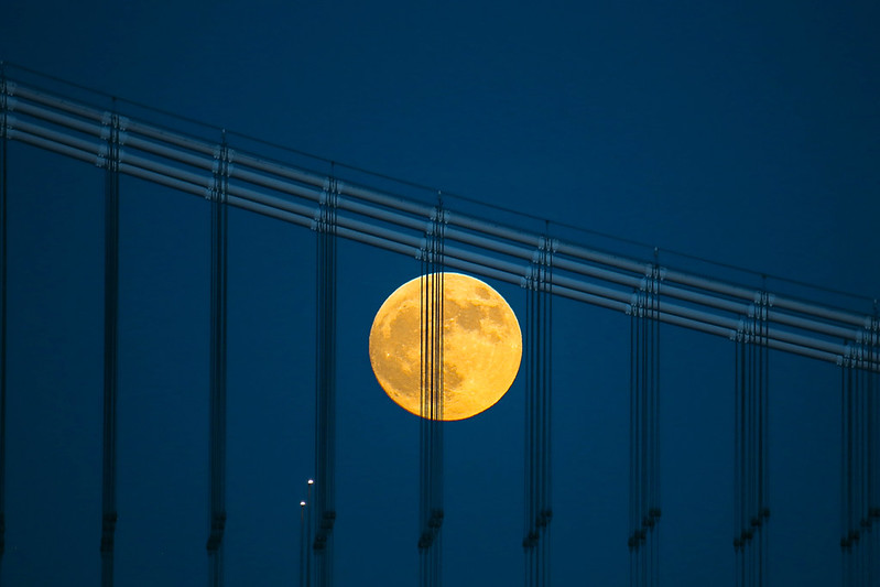 A shot of the full moon rising over the Manhattan Bridge