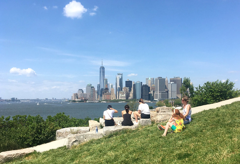 people sit in a park in Brooklyn with a view of lower Manhattan