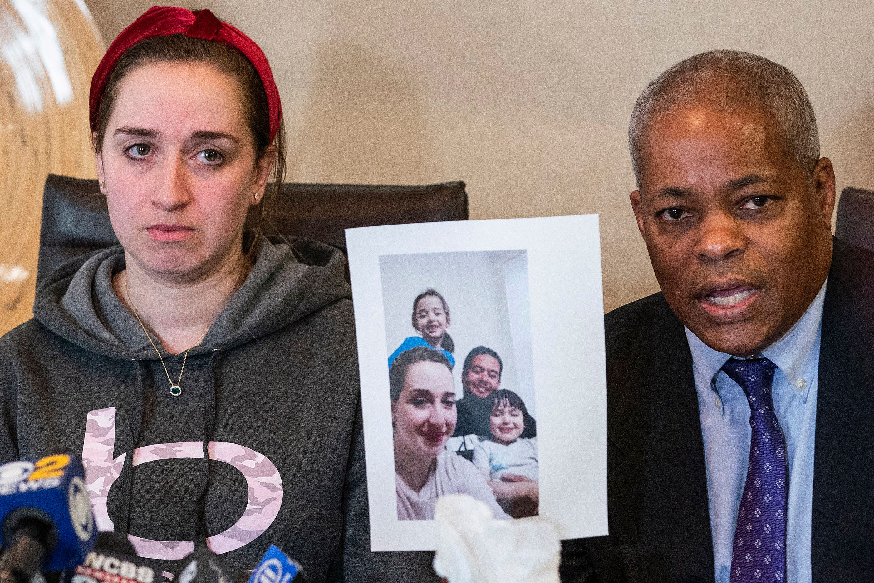 A woman sits next to her lawyer, who holds a picture of her family.
